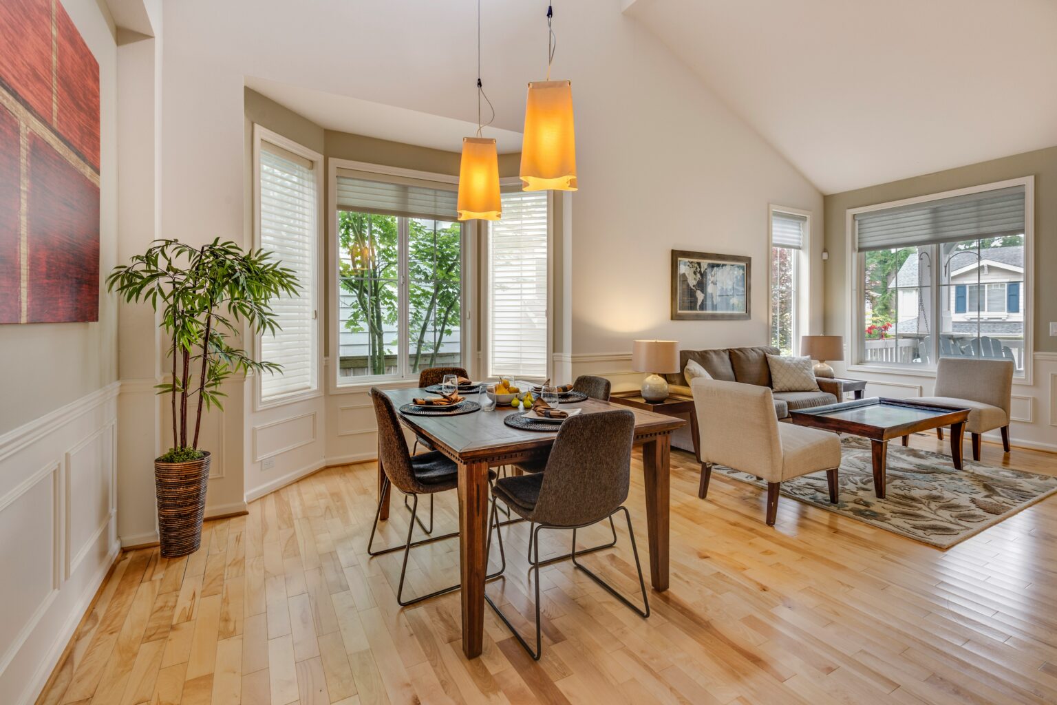 Combined living and dining room area with wooden floors and hanging pendant lights