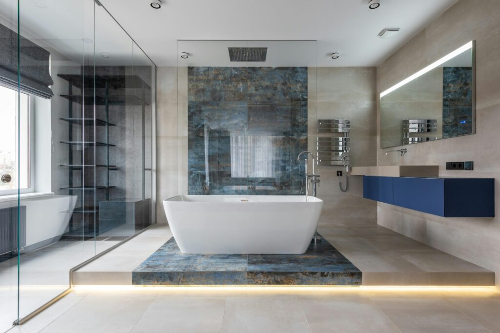 Beautifully renovated bathroom. White tub on top of a blue stone accent strip