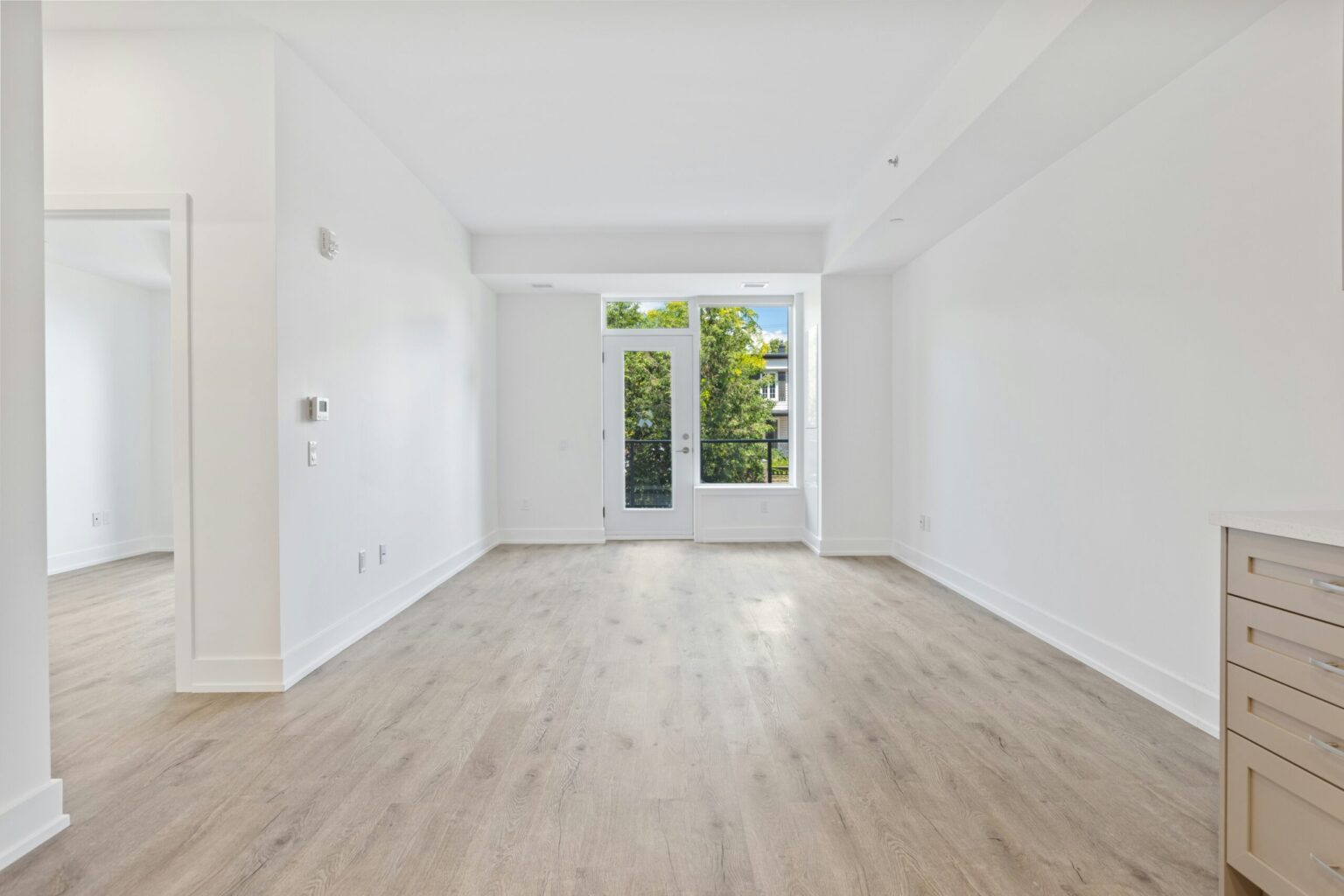 Empty room with white walls and honey colored floors