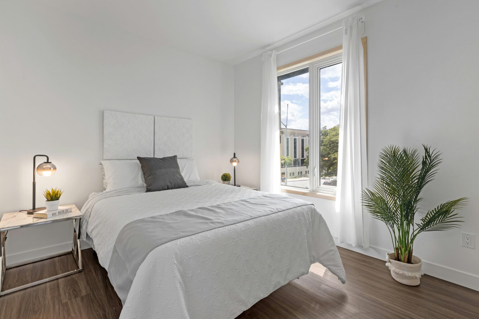 Bedroom with a window and a plant next to the bed
