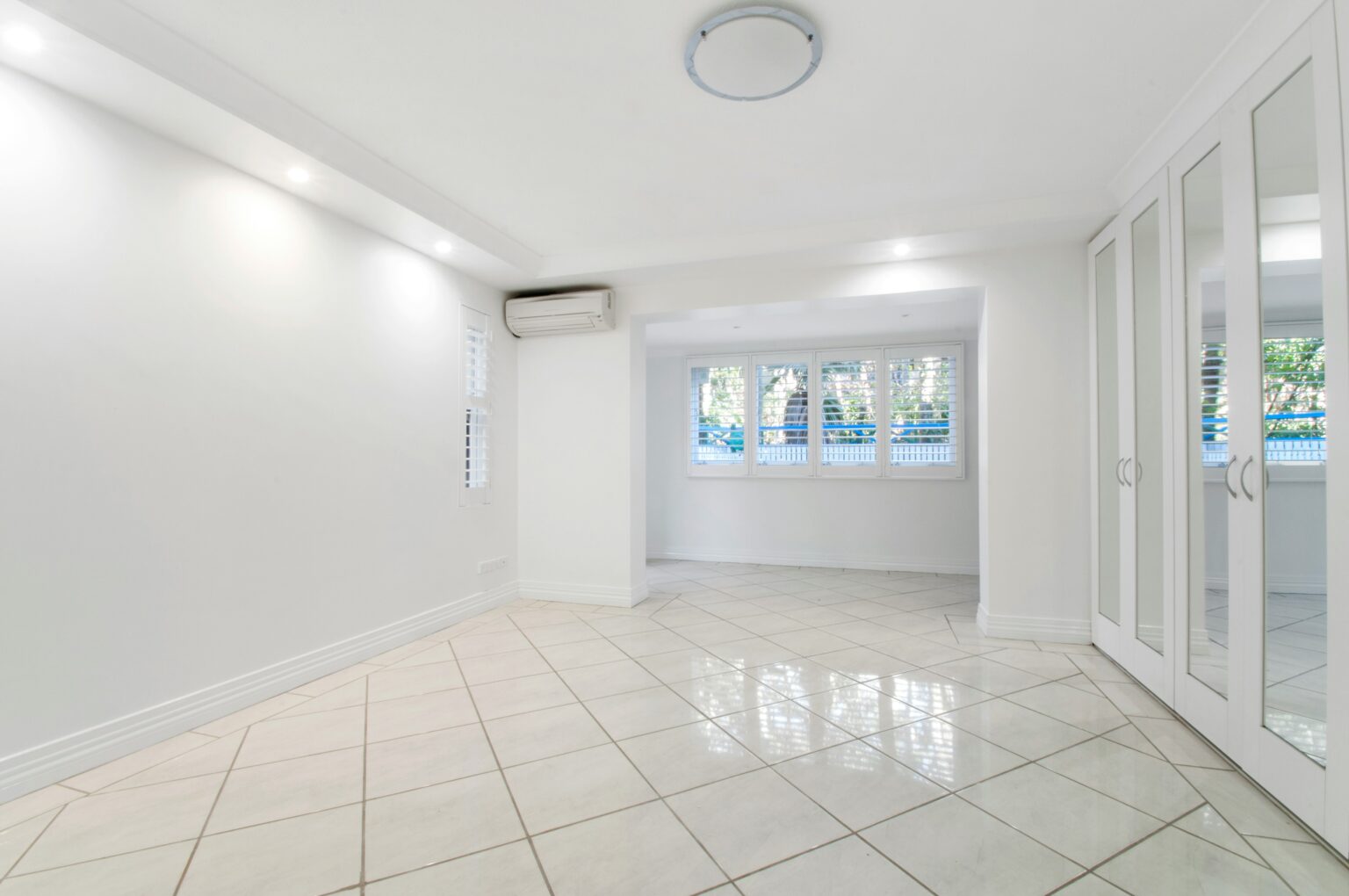Empty room with tile flooring, sliding doors, and several windows
